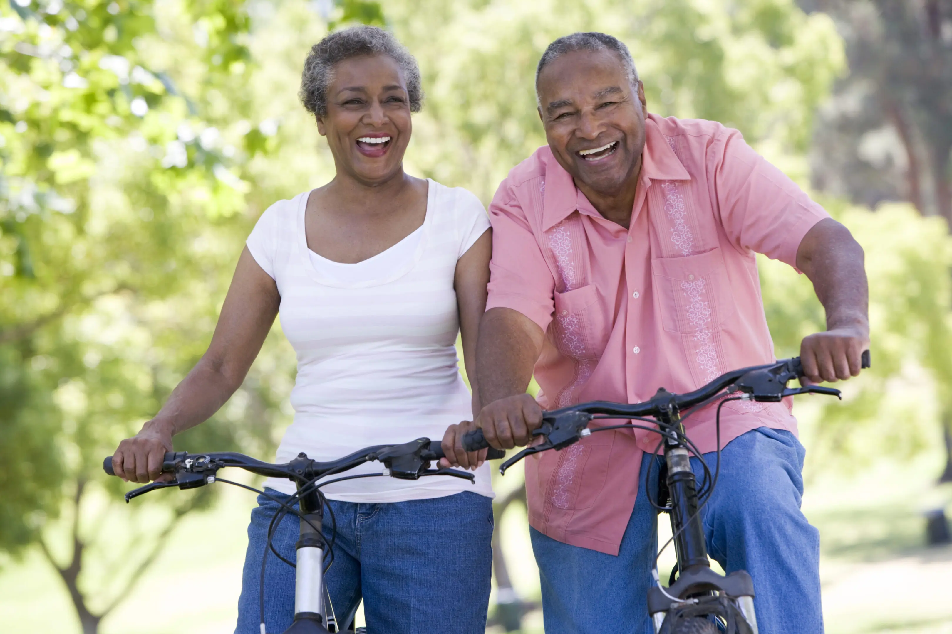 A man and woman riding bikes in the park.