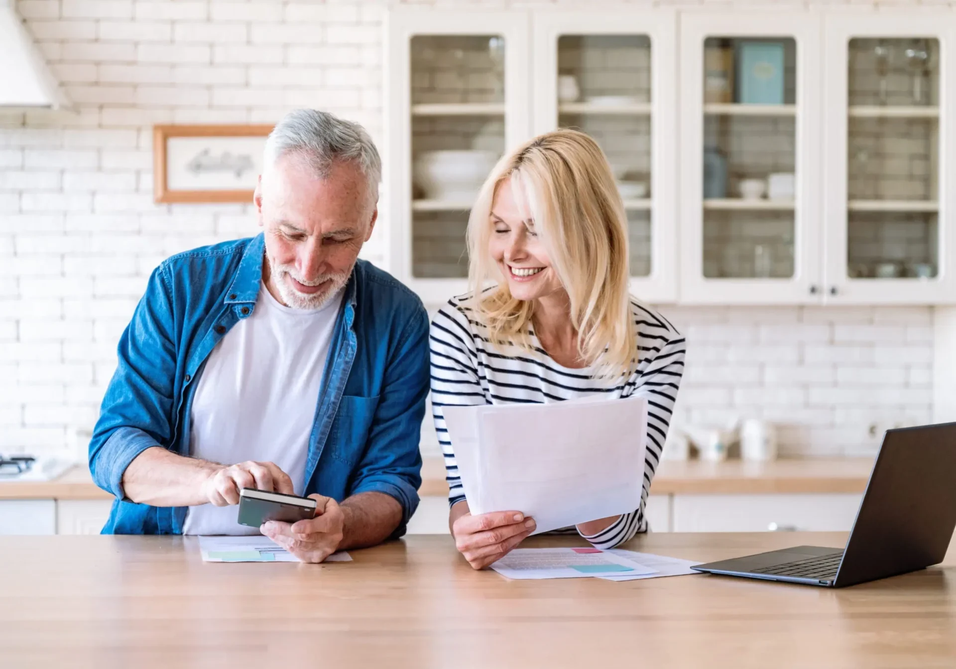 A man and woman sitting at a table looking at papers. A man and woman sitting at a table looking at papers.