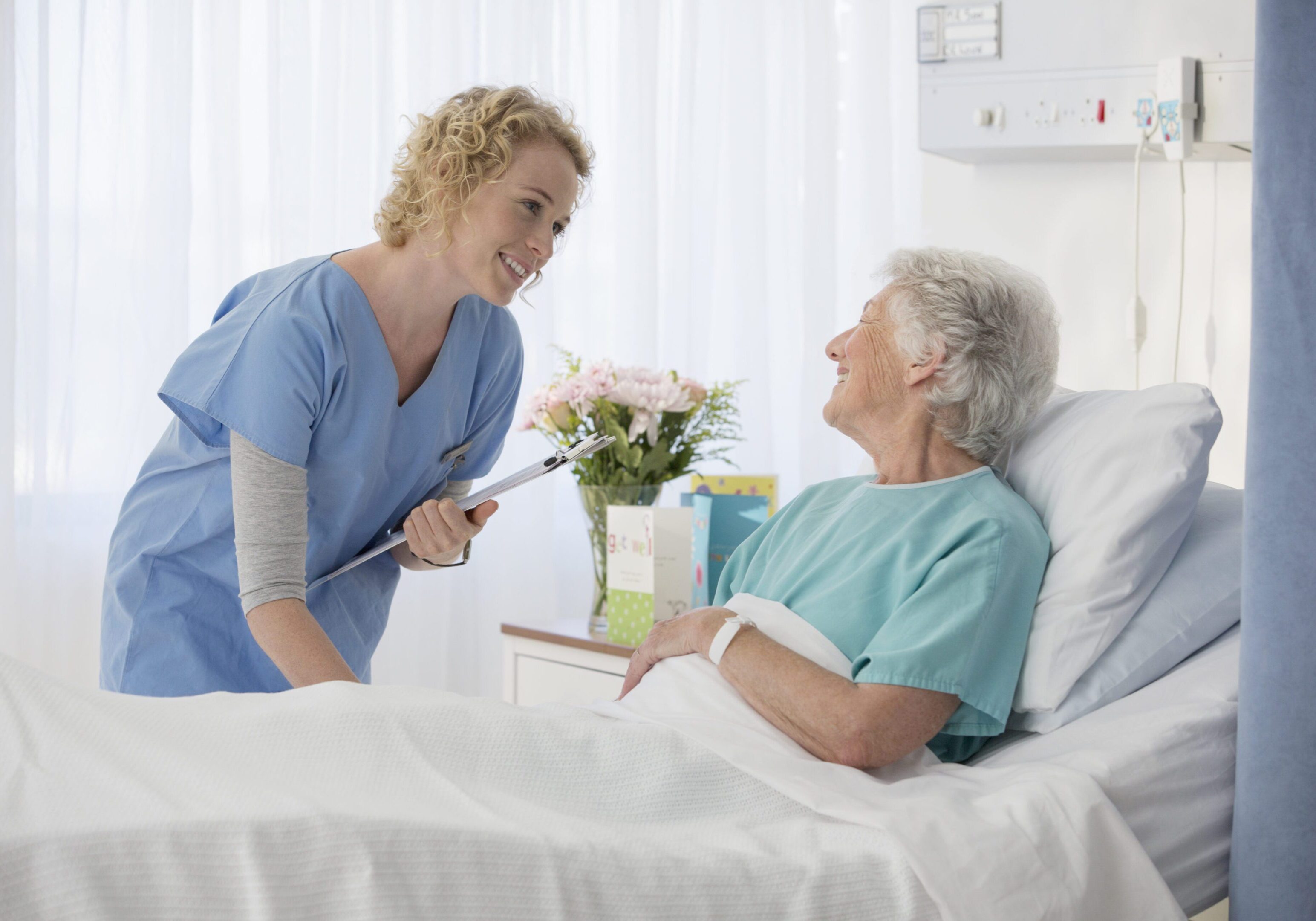 Nurse and aging patient talking in hospital room A nurse and an elderly patient in a hospital bed.